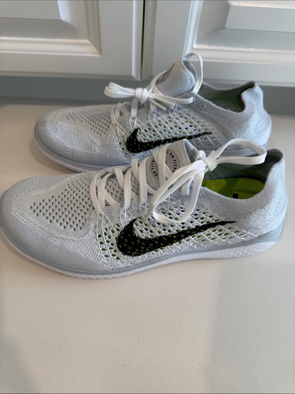 Nike womenโs Flyknit Athletic Shoes - White with Black Swoosh and Green Accents
